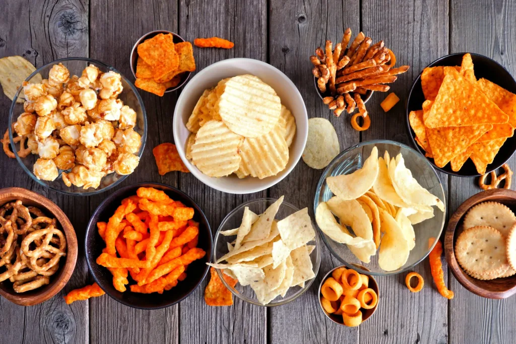Variety of salty snacks like chips, pretzels, nachos, popcorn, biscuits and cheese crackers